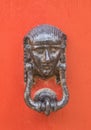 Decorative bronze traditional malttese door handle in the form of a beautiful woman`s head on a red painted door. Malta Royalty Free Stock Photo