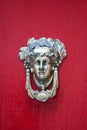 Decorative bronze traditional malttese door handle in the form of a beautiful woman`s head on a red painted door. Malta Royalty Free Stock Photo