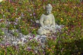 Decorative buddha statue in a flower garden of pansies