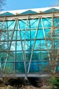 Decorative building facade reflective blue glass structure with arching trialgular layout metal beams wavy flat rooftop