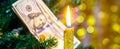 Decorative candle near Christmas tree. One hundred dollars ÃÂ¾n the Christmas tree_ Royalty Free Stock Photo