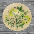 Decorative ceramic plate, hand painted dot pattern with acrylic paints on a gray wooden background. A square photo. Closeup