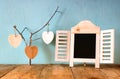 Decorative chalkboard frame and wooden hanging hearts over wooden table. ready for text or mockup. retro filtered image Royalty Free Stock Photo