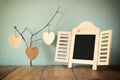 Decorative chalkboard frame and wooden hanging hearts over wooden table. ready for text or mockup. retro filtered image Royalty Free Stock Photo