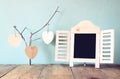 Decorative chalkboard frame and wooden hanging hearts over wooden table. ready for text or mockup. retro filtered image Royalty Free Stock Photo