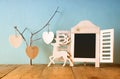 Decorative chalkboard frame and wooden hanging hearts over wooden table. ready for text or mockup. retro filtered image Royalty Free Stock Photo