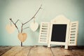 Decorative chalkboard frame and wooden hanging hearts over wooden table. ready for text or mockup. retro filtered image Royalty Free Stock Photo