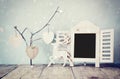 Decorative chalkboard frame and wooden hanging hearts over wooden table. ready for text or mockup. retro filtered image Royalty Free Stock Photo