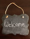 Decorative Chalkboard with a welcome written in chalk on Wood Background