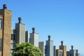 Decorative chimneys in row in neighborhood with wooden slats or panels with metal tops and gradient blue and white sky Royalty Free Stock Photo