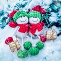 Decorative Christmas and Happy New Year composition of funny two snowmen in hats and scarves with presents seating in the snow. Royalty Free Stock Photo