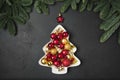 Decorative Christmas tree as plate with red and golden balls on black. Xmas greeting card. View from above, flat lay Royalty Free Stock Photo