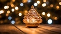A decorative christmas tree on top of a wooden table lit up in bokeh