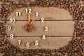 Decorative clock with wooden numerals and arrows made of cinnamon sticks, showing 1 hour, on a wooden background and a frame of co