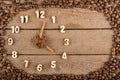 Decorative clock with wooden numerals and arrows made of cinnamon sticks, showing 4 o`clock, on a wooden background and a frame of
