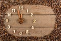 Decorative clock with wooden numerals and arrows made of cinnamon sticks, showing 12 o`clock, on a wooden background and a frame o