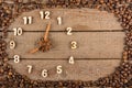 Decorative clock with wooden numerals and arrows made of cinnamon sticks, showing 8 o`clock, on a wooden background and a frame of