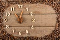 Decorative clock with wooden numerals and arrows made of cinnamon sticks, showing 11 o`clock, on a wooden background and a frame o