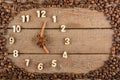 Decorative clock with wooden numerals and arrows made of cinnamon sticks, showing 5 o`clock, on a wooden background and a frame of