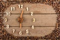 Decorative clock with wooden numerals and arrows made of cinnamon sticks, showing 6 o`clock, on a wooden background and a frame of