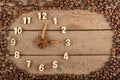 Decorative clock with wooden numerals and arrows made of cinnamon sticks, showing 3 o`clock, on a wooden background and a frame of