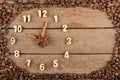 Decorative clock with wooden numerals and arrows made of cinnamon sticks, showing 10 o`clock, on a wooden background and a frame o