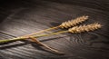 Two ripe wheat ears on a wooden table. Triticum aestivum