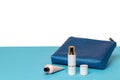 Decorative composition of a female blue cosmetic travel bag and bottles of cosmetic products on blue desk isolated on a white Royalty Free Stock Photo