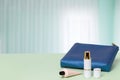 Decorative composition of a female blue cosmetic travel bag and bottles of cosmetic products on green desk over windows background