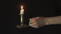 Decorative copper candlestick with burning candles in a female left hand on a black background