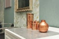 Decorative copper containers on a white chest of drawers and