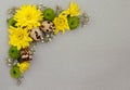 Decorative corner of yellow, green and white flowers with quail eggs on gray paper