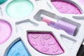 Decorative cosmetics for kids. Eye shadow palette with lipstick as background, closeup