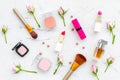 Decorative cosmetics layout. Pink tones of lipstick, bulk, eyeshadow, perfume, brushes among rose flowers on white Royalty Free Stock Photo