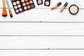 Decorative cosmetics set with eyeshadow, rouge, lipstick, brushes on white desk background top view copy space