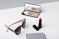 Decorative cosmetics sunglasses and notebook on white table.