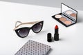 Decorative cosmetics sunglasses and notebook on white table.