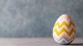 Decorative Easter egg with yellow and blue zigzag patterns placed on a soft textured background for a modern festive Royalty Free Stock Photo