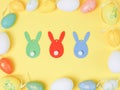 Decorative Easter eggs lie in a frame with three wooden bunnies on a yellow background Royalty Free Stock Photo