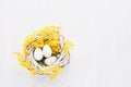 Decorative Easter eggs and mimosa wreath on a white background. Flat lay, copy space Royalty Free Stock Photo