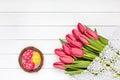 Decorative Easter eggs in nest and red tulips on white wooden table. Copy space, top view.Decorative Easter eggs in nest and red t Royalty Free Stock Photo