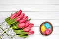 Decorative Easter eggs in nest and red tulips on white wooden table. Copy space, top view. Royalty Free Stock Photo