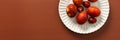 Decorative Easter eggs in various shades of red and orange sit on a white plate on a brown background, showcasing Royalty Free Stock Photo