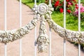 Decorative element of vintage forged white fence with garlands of flowers