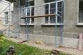 Decorative facade lime plastering, stucco working place with scaffoldings and building materials in a mess near the house