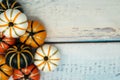 Decorative fake pumpkins white, orange and black with gold glitter details arranged on a blue wooden background.