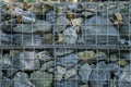 Decorative fence of bulk stone in the grid. Textured background of a stone wall with iron netting. Stone wall in wire frame. Royalty Free Stock Photo