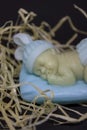 decorative figure of a sleeping baby on a blue pillow in straw