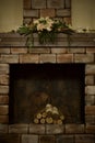 Decorative fireplace with birch logs, with a chimney fragment and composition of artificial flowers decorating