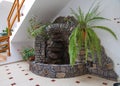 Decorative fireplace laid out of stones of different shapes in the room near the wall with pots standing on it with Royalty Free Stock Photo